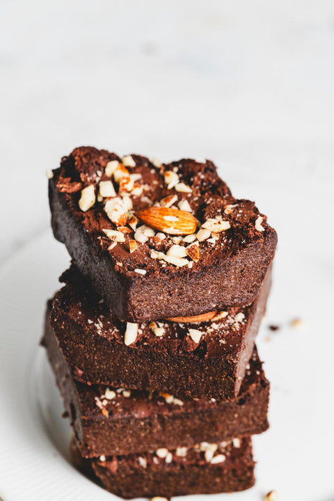 A stack of sugar free keto brownies with a crushed almond topping