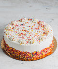 Vanilla birthday cake with white frosting amd colorful sprinkles.