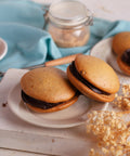 Chocolate chip whoopies with chocolate frosting on a white plate with white flowers