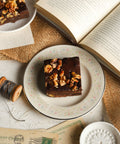 Walnut brownies on decorative plates next to a book and vintage postcards