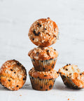 Stack of chocolate chip muffins with a crumb topping, arranged on a light surface.