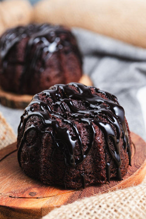 A chocolate bundt cake with chocolate glaze on a wooden tray