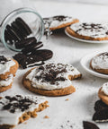 Frosted cookie crunch with white icing and crushed vegan Oreos, displayed on plates with scattered vegan oreos in the background.