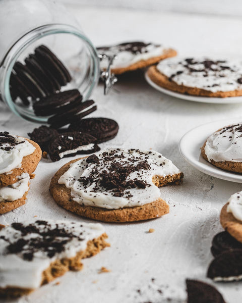 Frosted cookie crunch with white icing and crushed vegan Oreos, displayed on plates with scattered vegan oreos in the background.