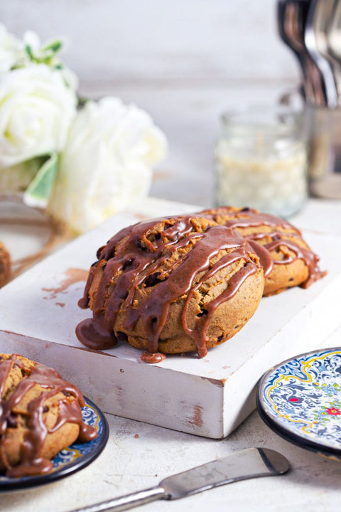 Cinnamon chocolate chip scones with cinnamon glaze on a white background with blue plates