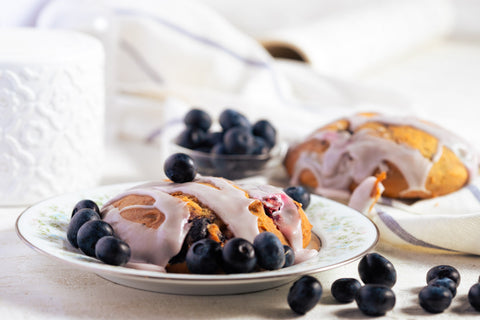 Blueberry lemon scones with lemon glaze and blueberries on a white plate with a blurred background