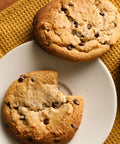 Chocolate chip cookies on a white plate with a yellow textured mat underneath