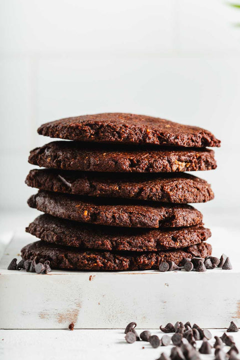 Stack of milk chocolate cookies on a white surface, with scattered chocolate chips.