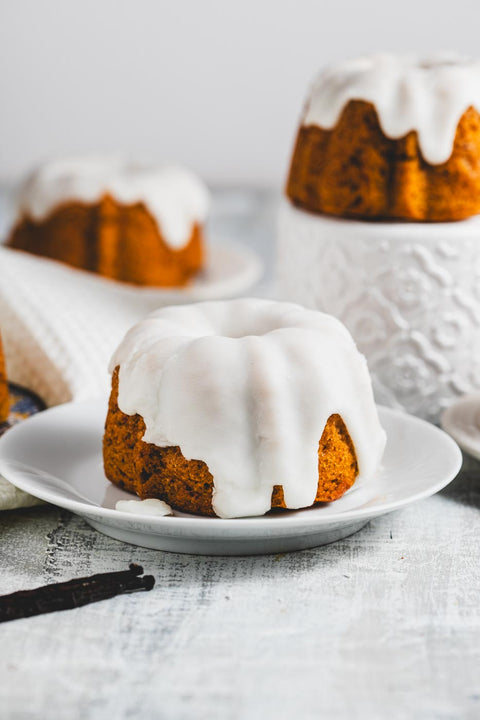 mini lemon pound bundt cakes with glaze on plates with vanilla beans