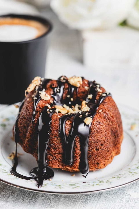 Close up of a mini banana bundt cakes with chocolate glaze and crushed walnuts