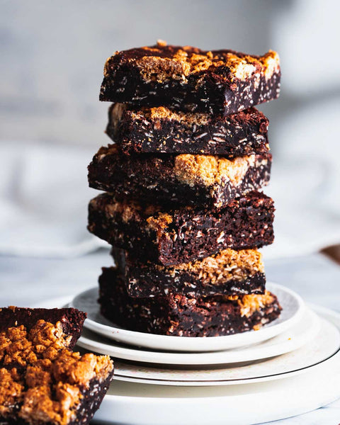 Stack of oatmeal brookies on a white plate with a single piece on the side and chocolate chunks scattered.