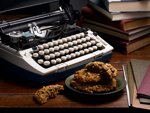 Energy cookies on a black plate with a vintage typewriter and books in the background, creating a cozy scene.