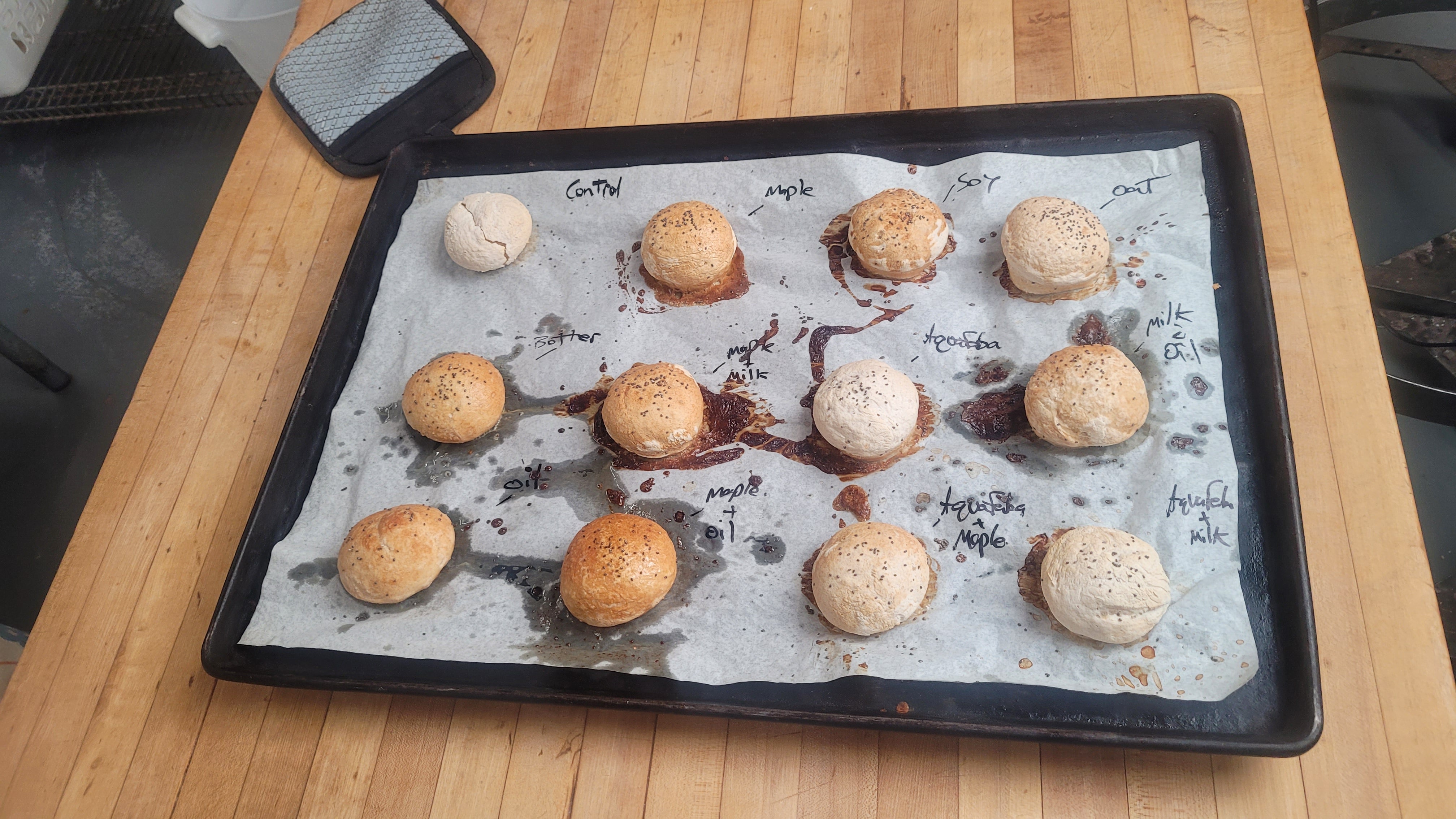 A tray of vegan gluten free bread rolls testing different egg wash alternatives.