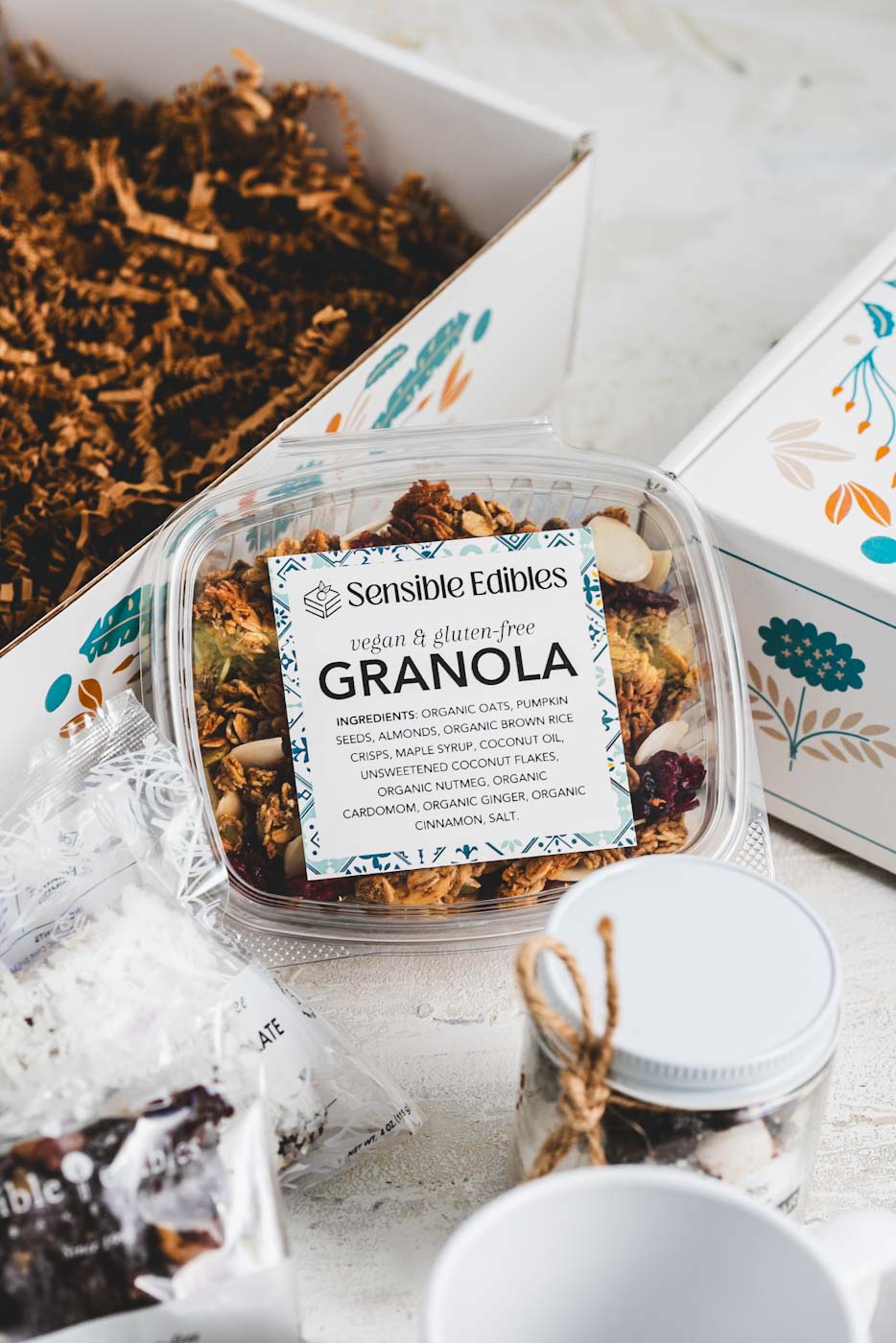 close up of granola package with open gift box in the background and other treats scattered around