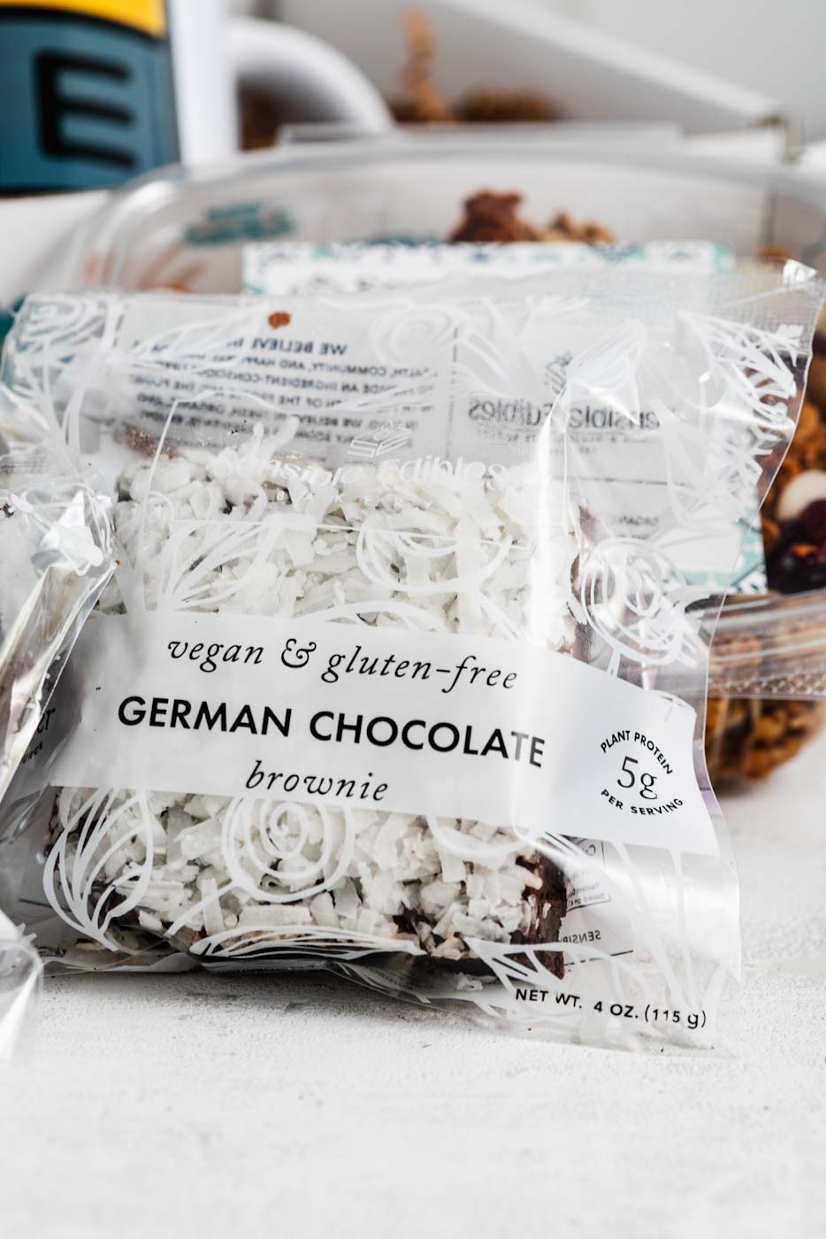 close up of packaged german chocolate brownie leaning against granola with an open gift box in the background