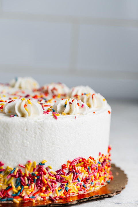 Vanilla birthday cake with white frosting and colorful sprinkles.