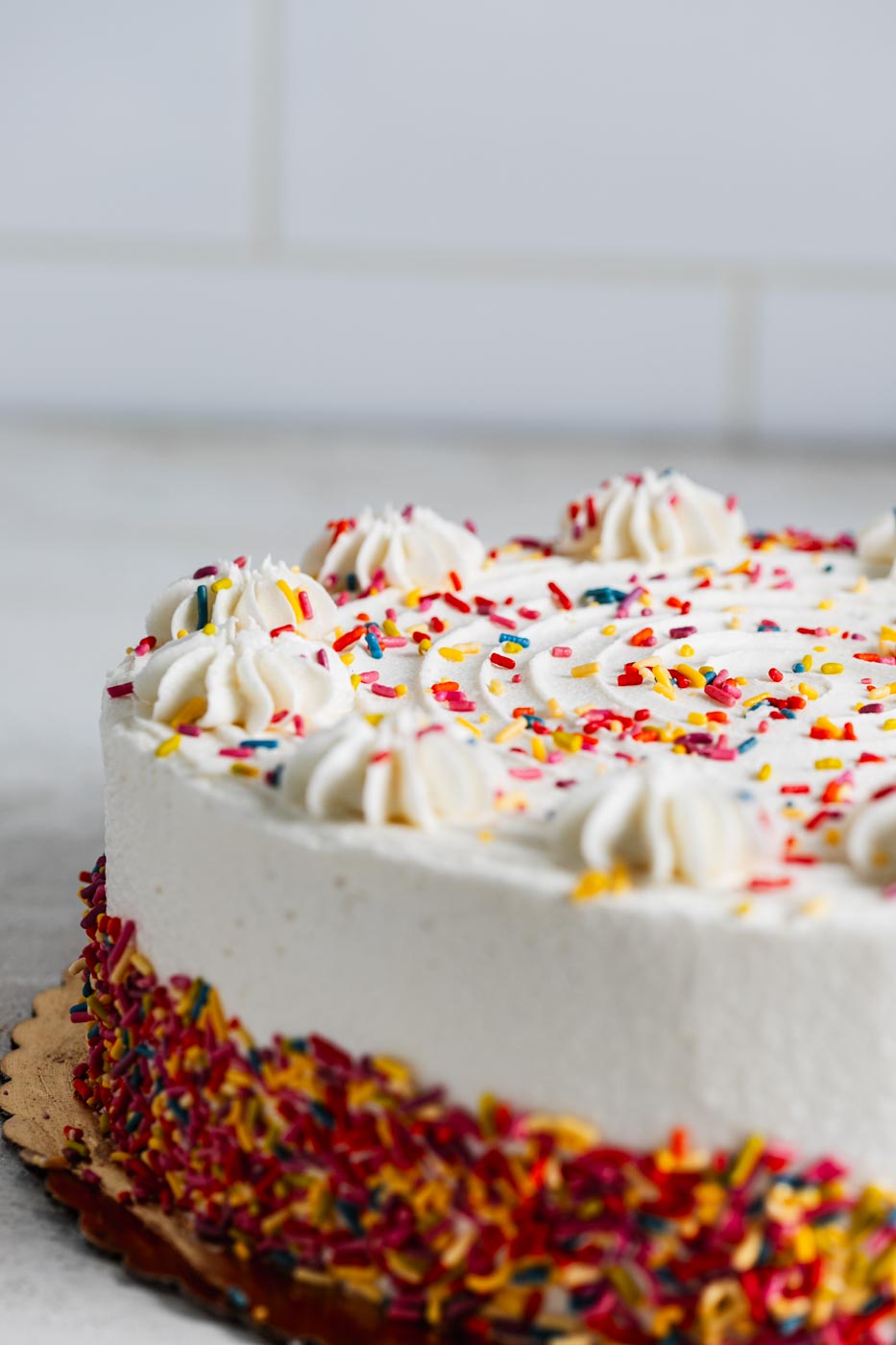 Vanilla birthday cake with white frosting amd colorful sprinkles.