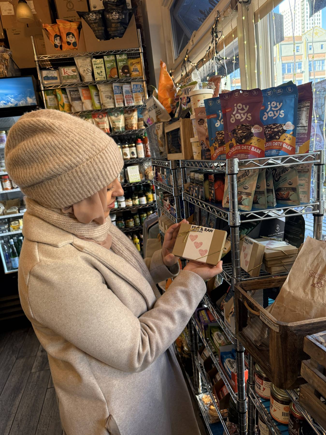 a woman in a vegan grocery store looking at a box of chocolates
