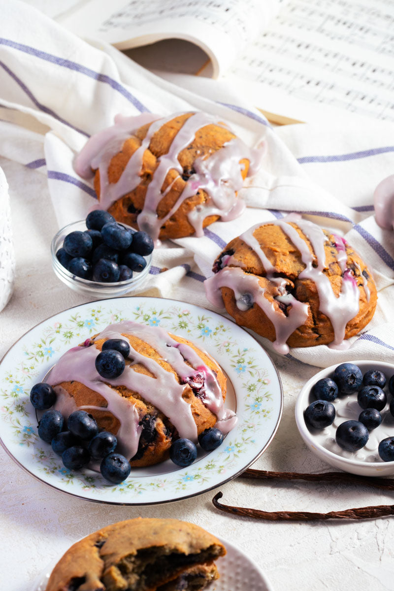Blueberry lemon scones with lemon glaze and blueberries on a white plate with a white napkin.