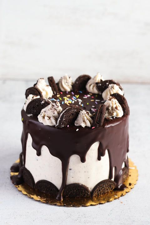 Cookies and cream cake with vanilla and chocolate frosting decorated with oreo cookies, sprinkles, and cookie crumbs