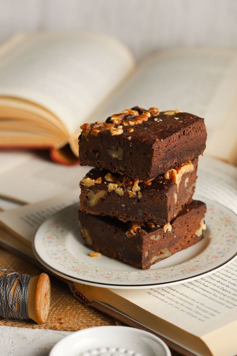 Stack of walnut brownies on a plate placed on an open book