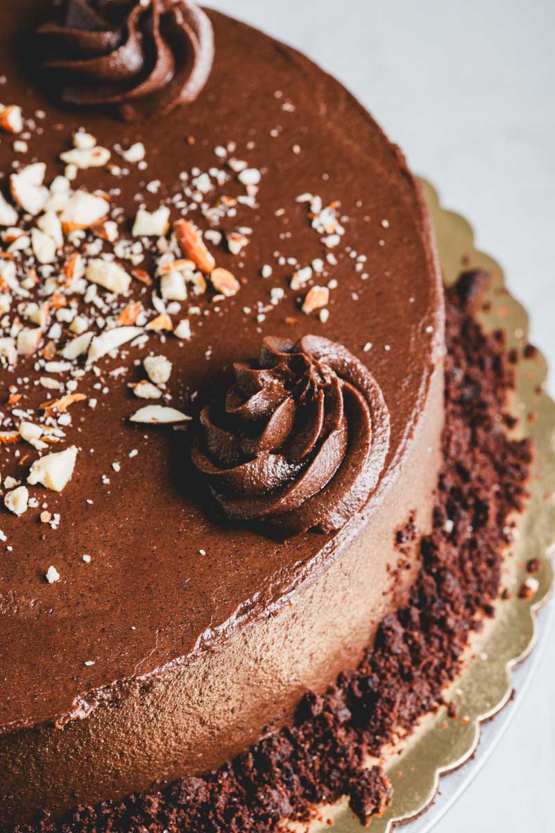 close up of keto chocolate cake with rich chocolate frosting and chocolate crumble and nut decoration