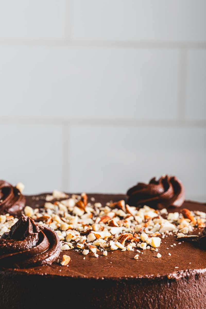 close up of keto chocolate cake with rich chocolate frosting and chocolate crumble and nut decoration
