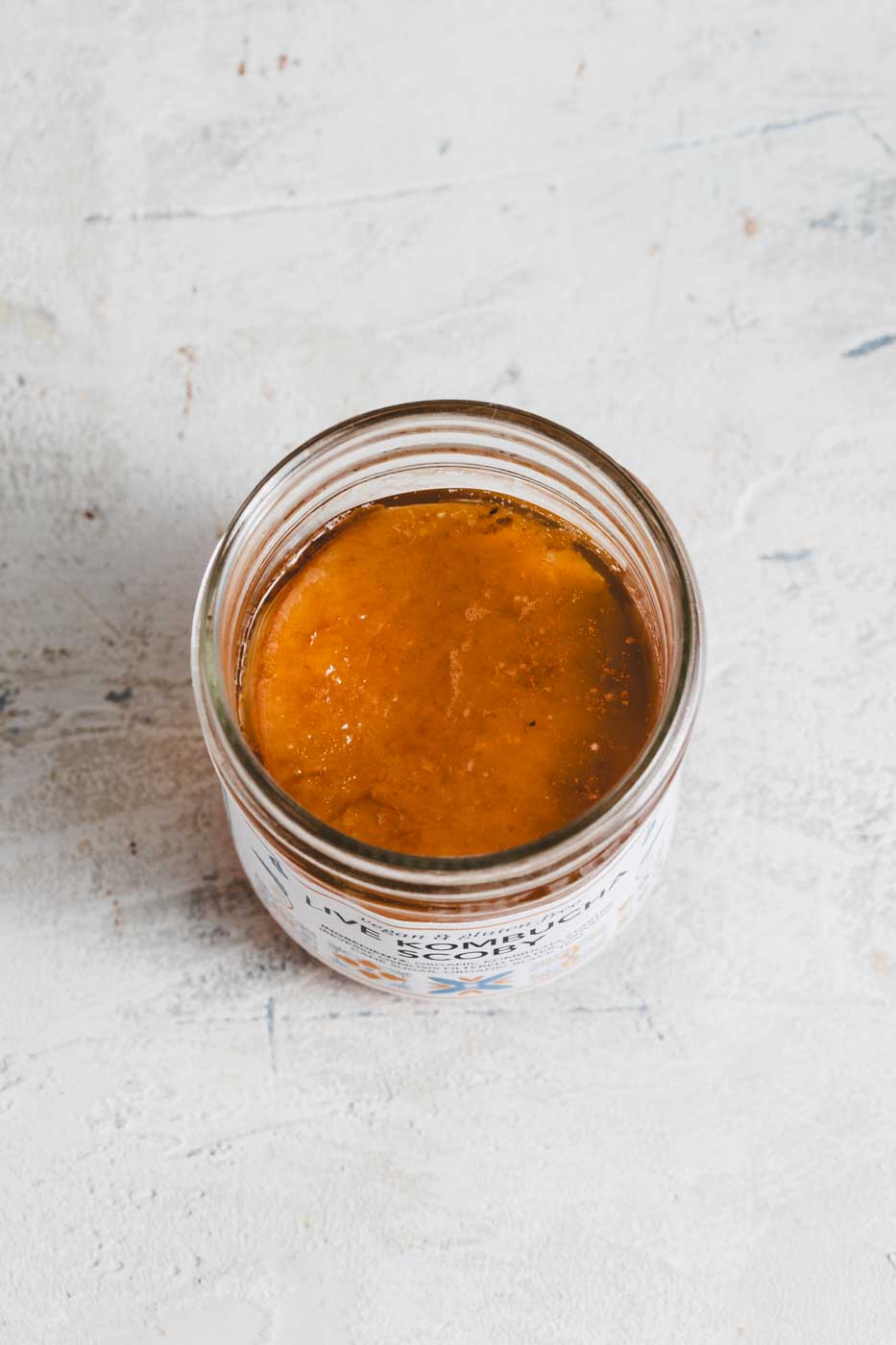 Open glass jar with a kombucha scoby inside seen from above