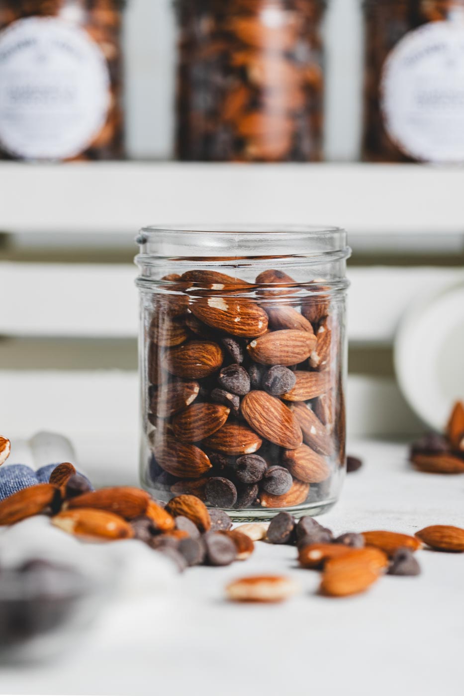 A close-up of a jar filled with whole almonds and chocolate chunks.