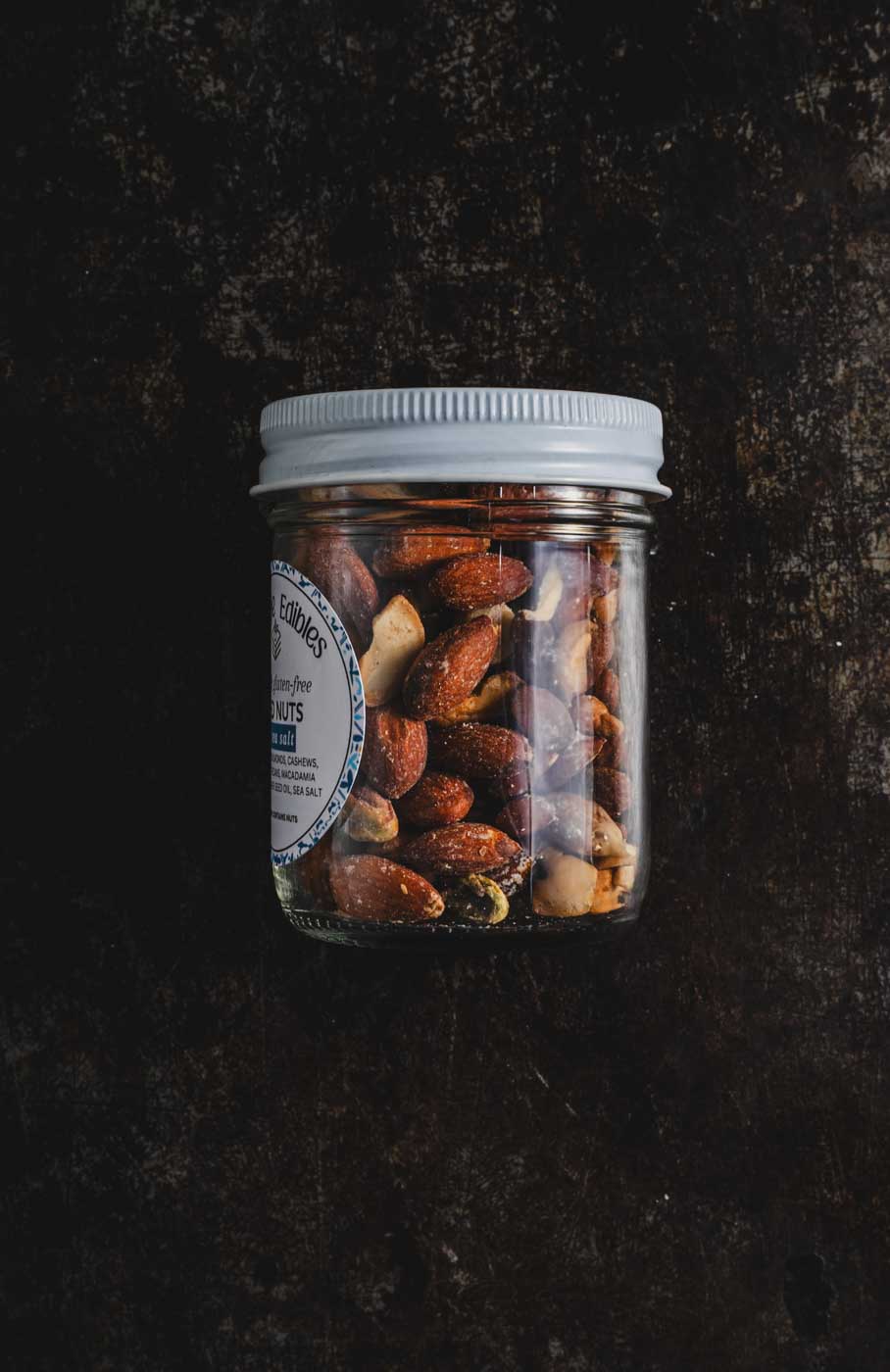 jar of salted mixed nuts turned to the side to show nuts on a dark background