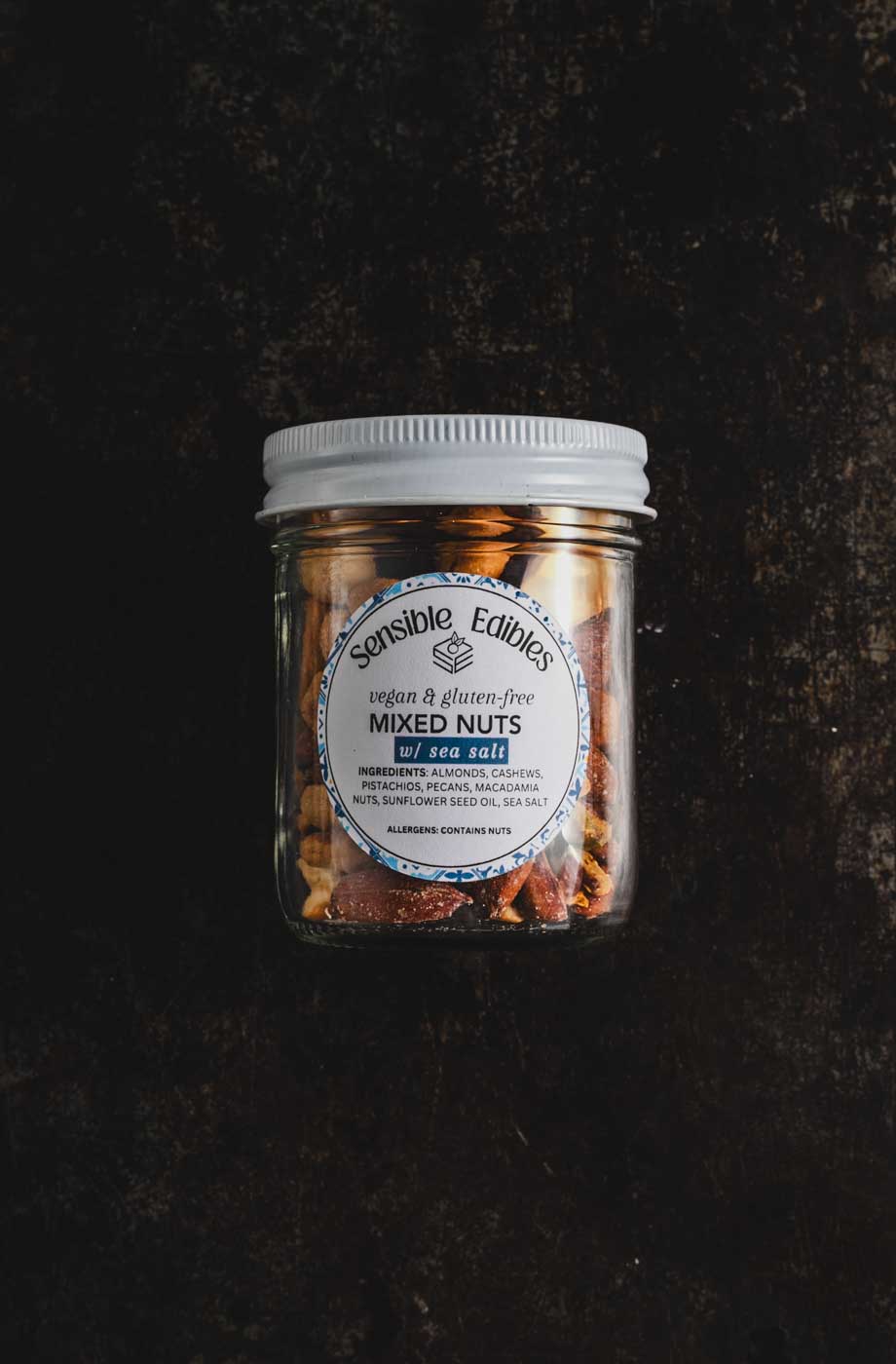 Jar of salted mixed nuts on a dark background