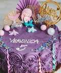 Purple birthday cake with decorative elements and 'Happy Birthday' topper