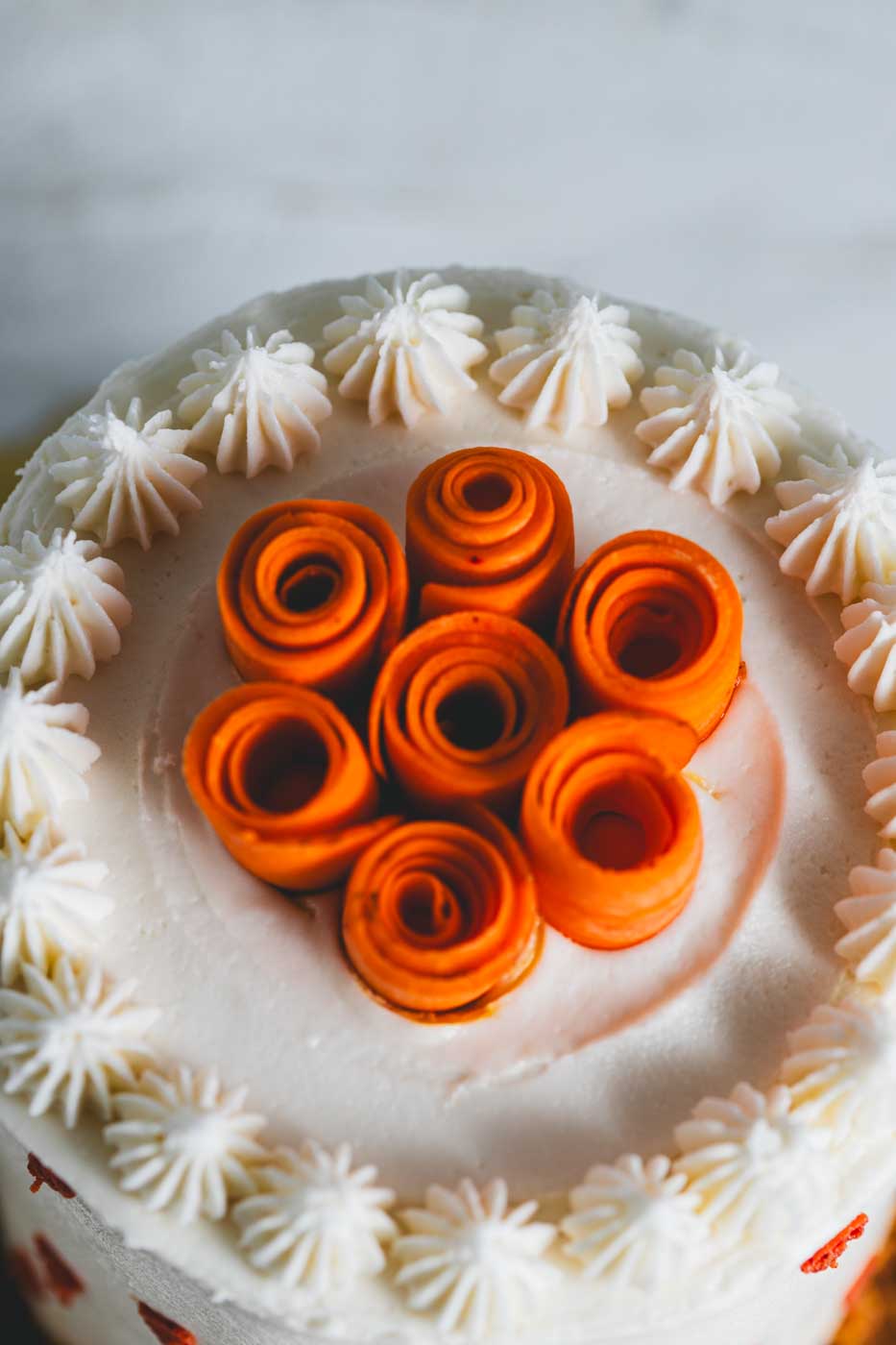 Carrot cake with decorative white frosting and a garnish of carrot "flowers"