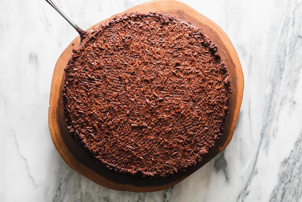 chocolate fudge cake with chocolate garnishes on a wooden tray