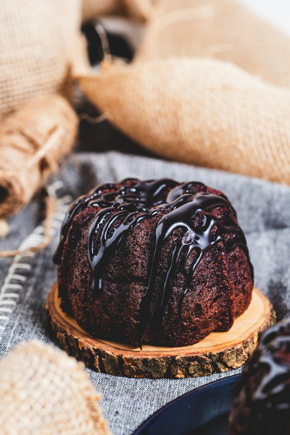 A chocolate bundt cake with chocolate glaze on a wooden tray