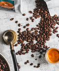 scattered coffee beans on a white background with a cup of coffee and bags of coffee beans