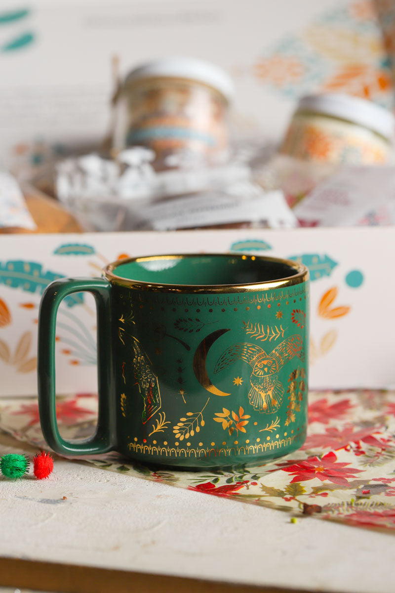 Green mug with gold designs on a patterned surface