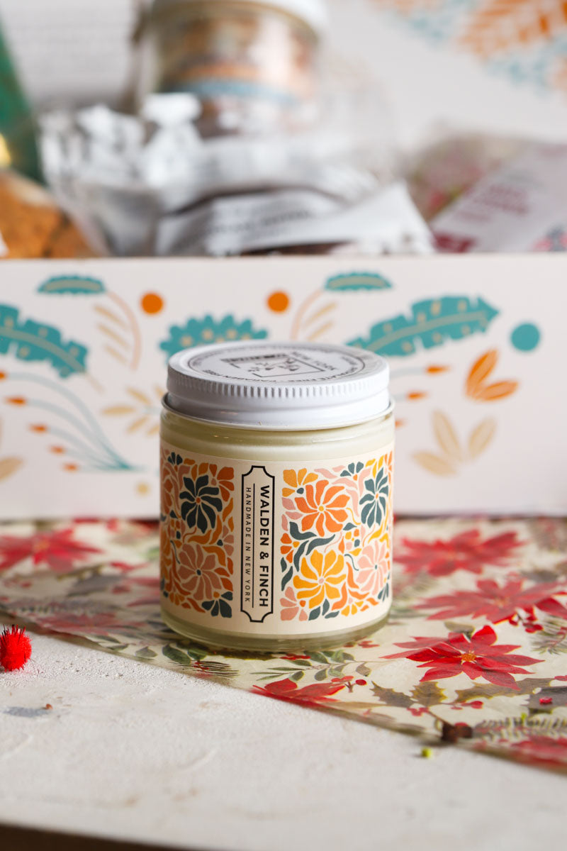 Candle jar with decorative label on a patterned surface