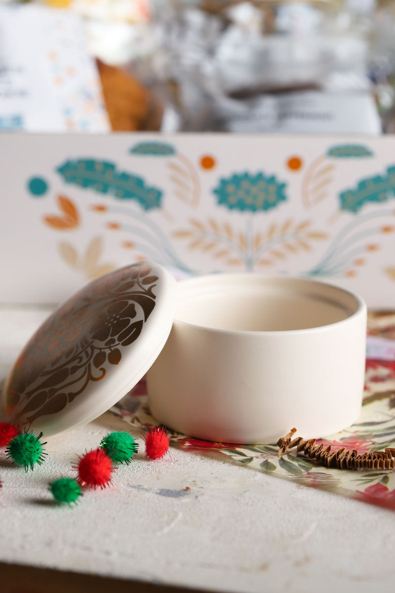 White ceramic bowl with a gold decorated lid on a patterned surface