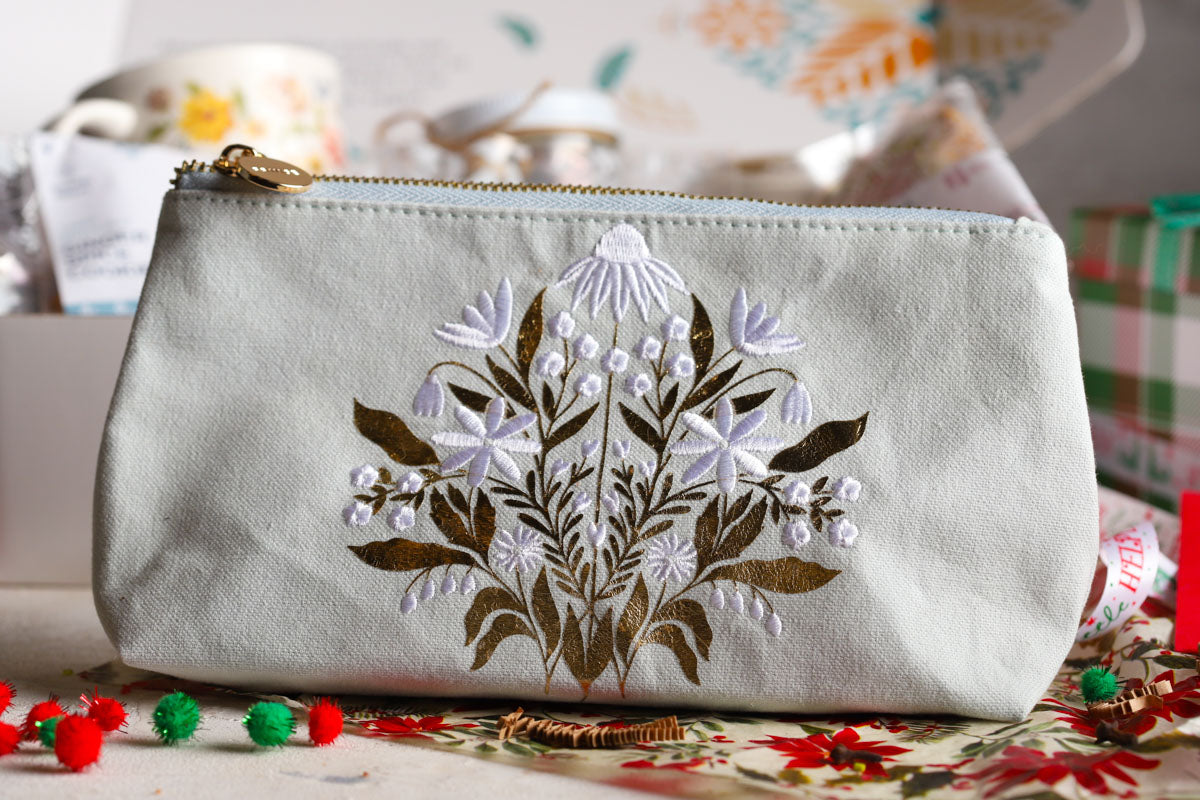 Light blue pouch with floral embroidery on a patterned surface