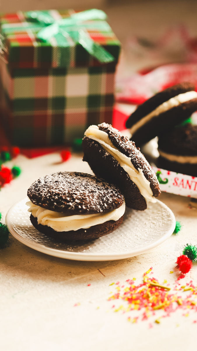 Chocolate peppermint whoopies on a plate with Christmas decorations in the background.