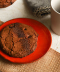 Espresso hazelnut cookie on a red plate with a white mug and gray napkin in the background.