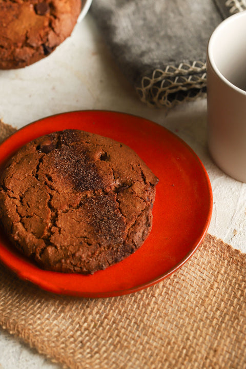 Espresso hazelnut cookie on a red plate with a white mug and gray napkin in the background.