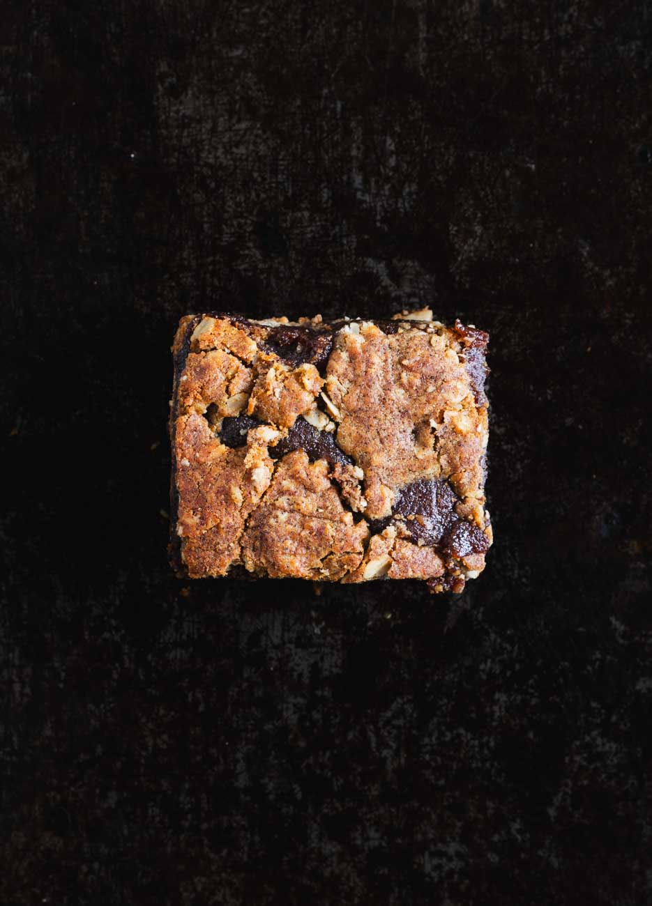 Single orange date bar showing a textured top with oats and date filling on a dark background.