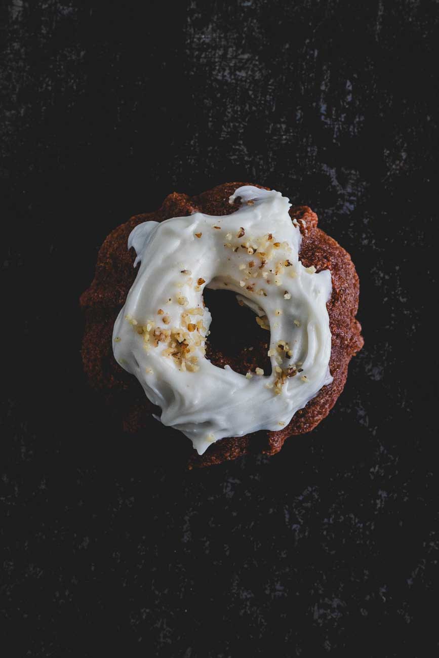 Top down view of a mini carrot walnut bundt cake with icing and crushed walnuts on top