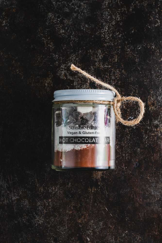 Upright hot chocolate jar with visible ingredients and twine on a dark background.