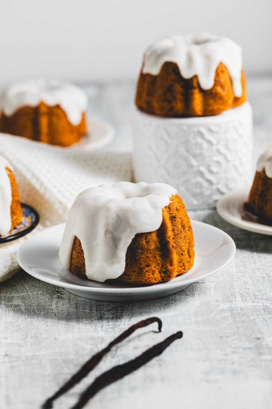 mini lemon pound bundt cakes with glaze on plates with vanilla beans