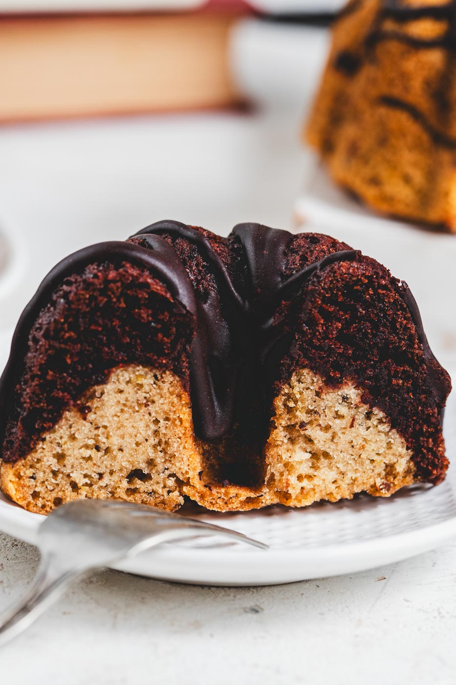 mini marble bundt cake with chocolate glaze cut in half on a plate