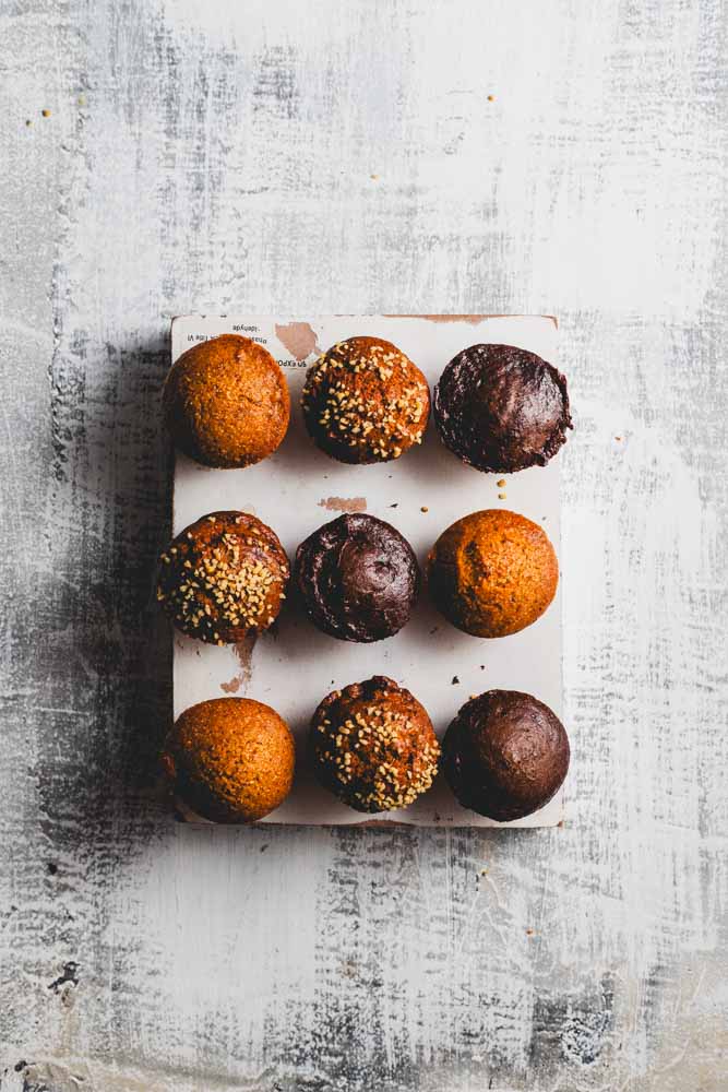 Nine mini muffins of different types arranged in rows of three on a white background