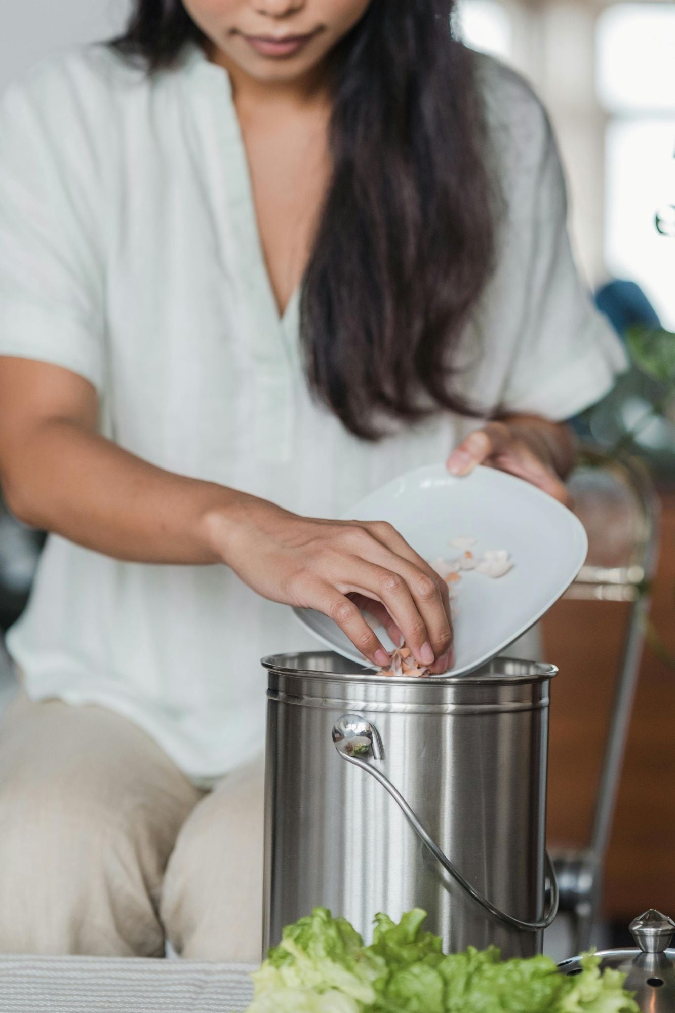 A person emptying food scraps into a countertop compost bin